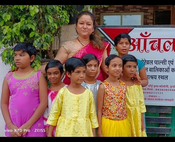 Founder Sumitra Mishra with girls from Aanchal Home in front of the trust's sign