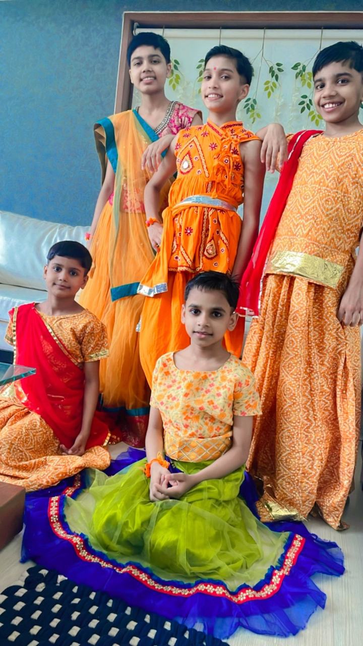 Three children in orange and green festival costumes